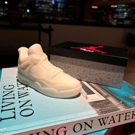 White sneaker candle and Jordan box on a book with a blurred cityscape background