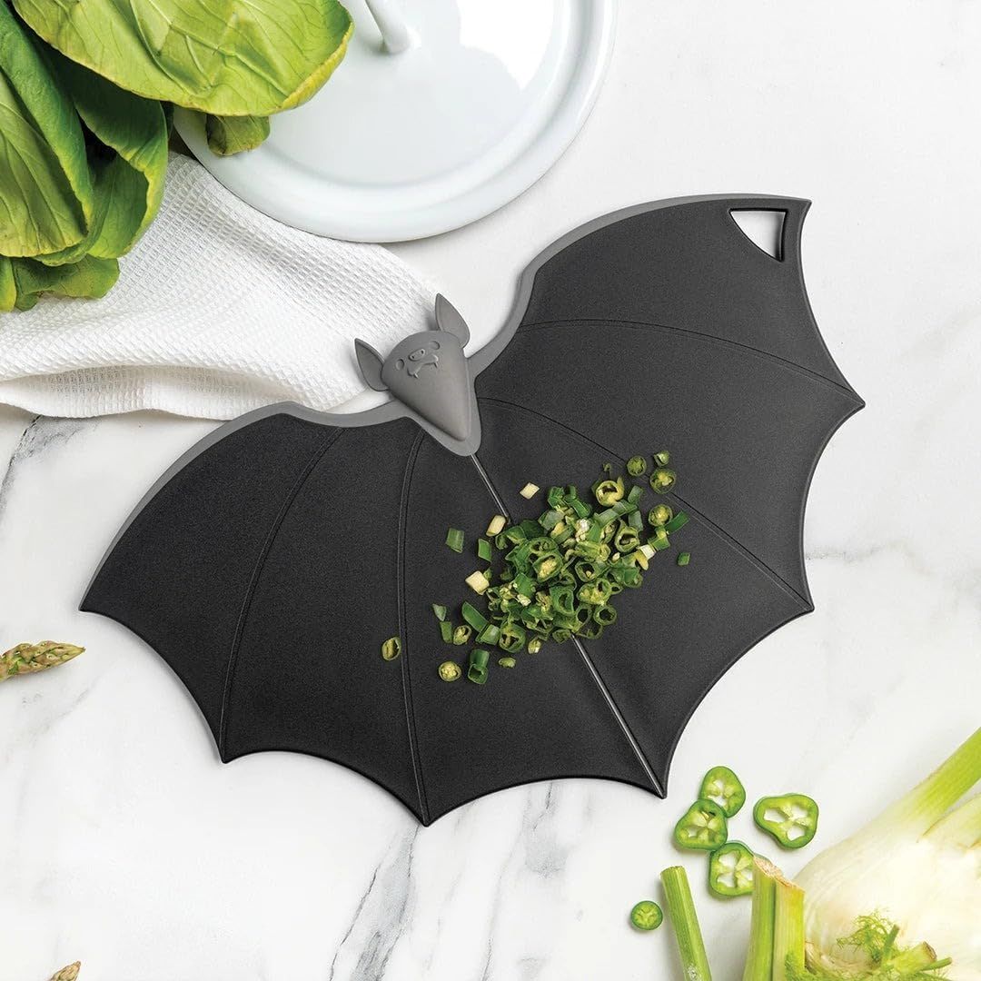 Silicone bat-shaped cutting board with chopped vegetables on a marble surface