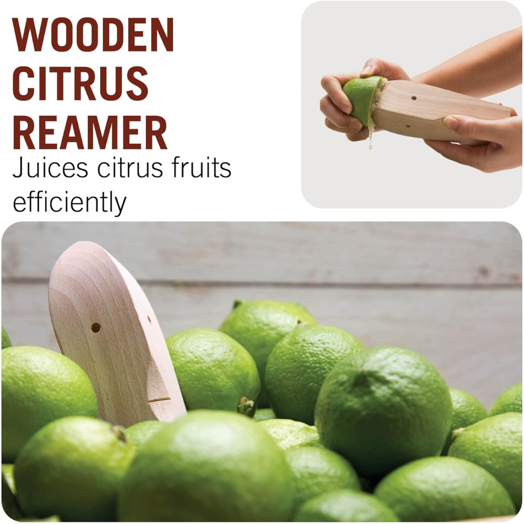 Wooden citrus reamer shaped like a face being used to squeeze a lime, shown among a pile of fresh green limes.