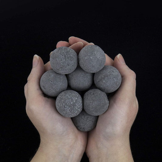 Hands holding a bunch of black goth bath bombs against a black background