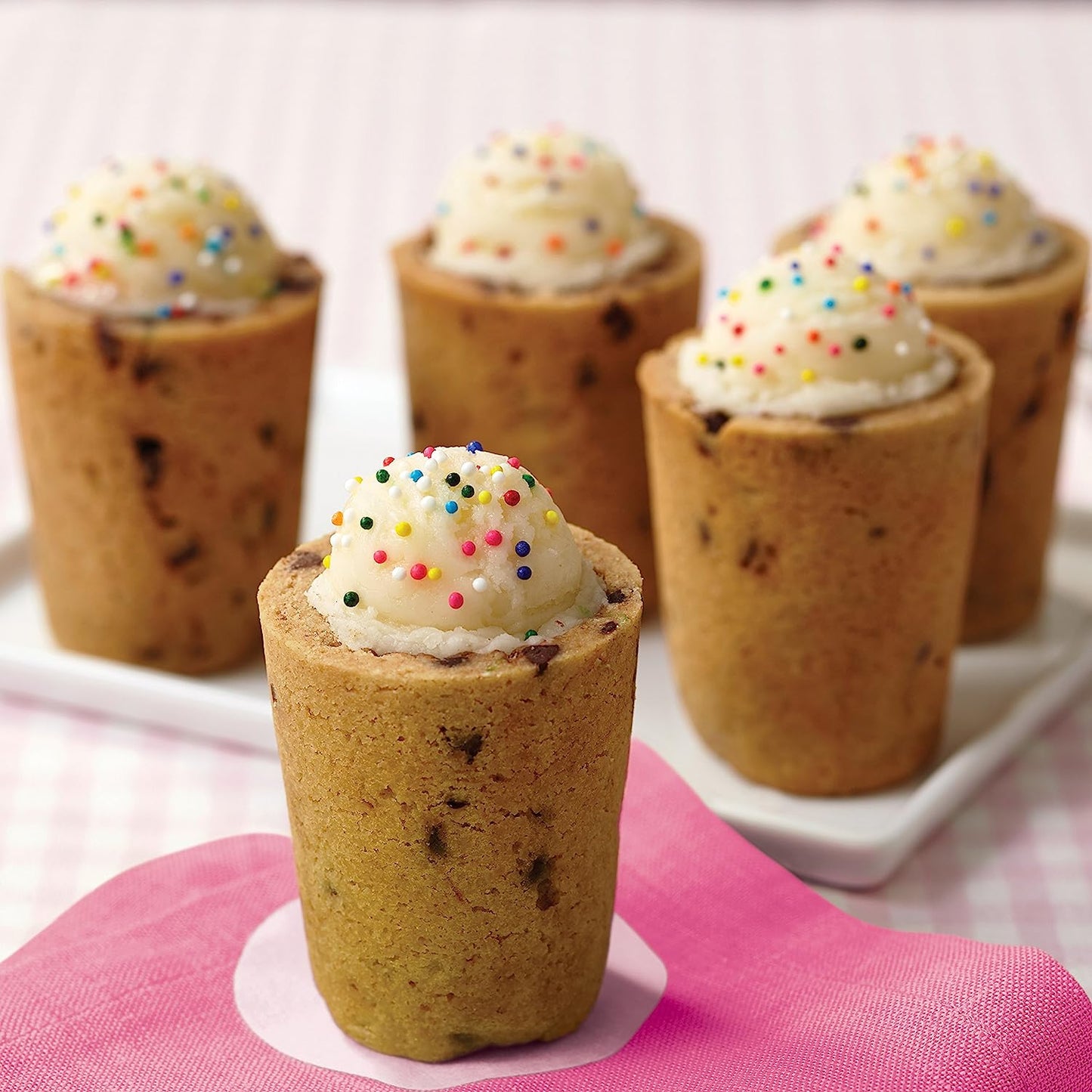 Shot glasses made from cookie dough which are filled with sweet treats.