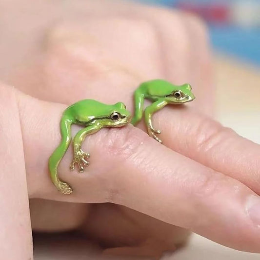 Two green frog rings on a person's finger with a blurred background