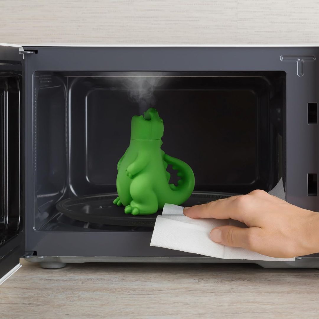 Green dragon-shaped microwave steam cleaner releasing steam inside a microwave to help loosen food residue and grime