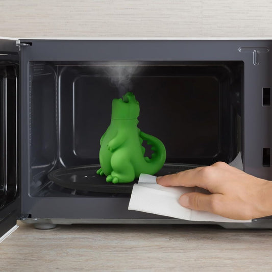 Green dragon-shaped microwave steam cleaner releasing steam inside a microwave to help loosen food residue and grime