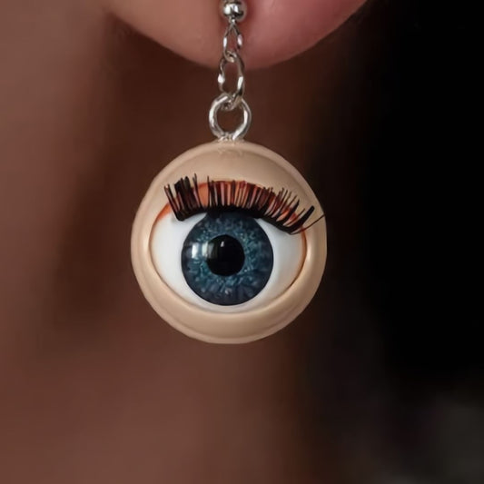 Eyeball-shaped earring with blue eye detail worn on an ear.