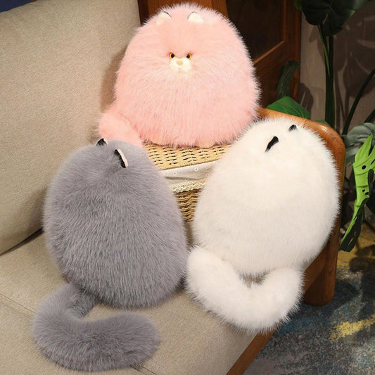 Three fluffy plush cat toys in pink, gray, and white sitting on a chair.