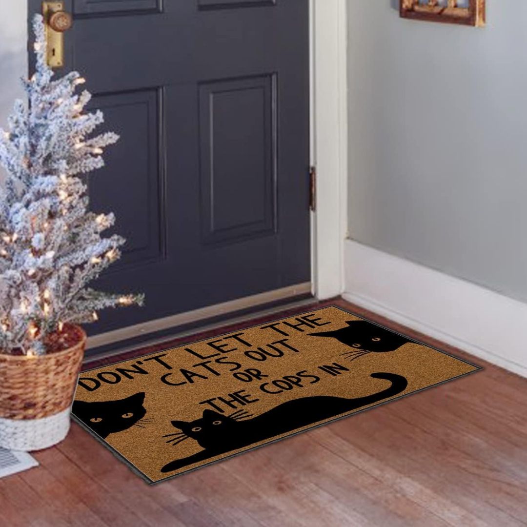A brown door mat featuring three black cats with text that reads, "don't let the cats out or the cops in." in front of a blue door.
