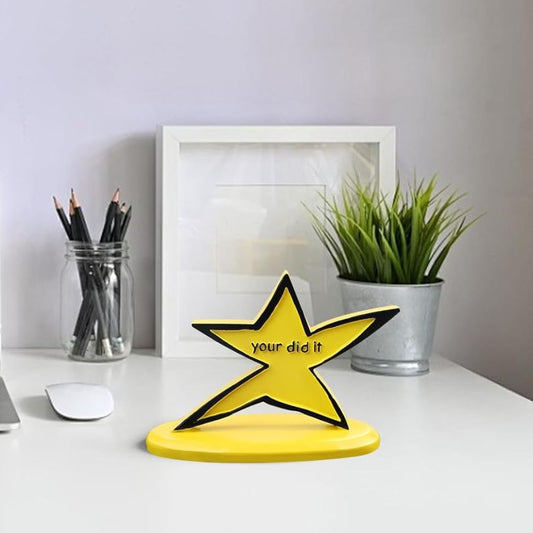 A funny yellow star shaped trophy with text, 'your did it' on an office desk.