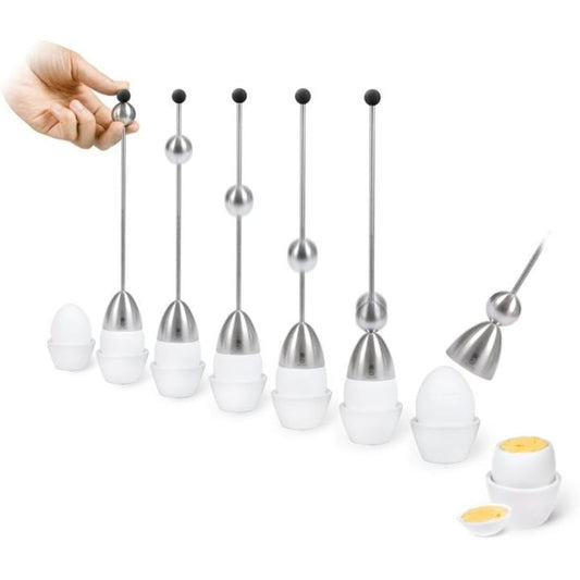 A set of stainless steel egg toppers with a number of cooked eggs in egg holders. A human hand is visible holding one of the long metal tools, and two cooked eggs are shown at the bottom right.