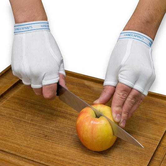 White fingerless Handerpants underwear gloves worn while slicing an apple on a wooden cutting board