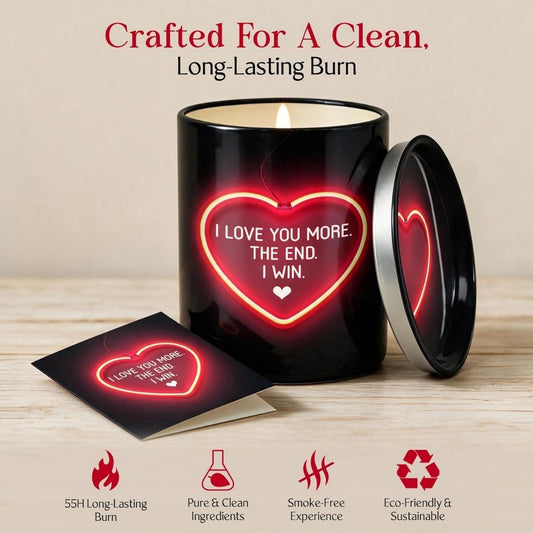 A black candle jar with a matching lid and a small card, both lit with a glowing red heart graphic that reads 'I LOVE YOU MORE. THE END.