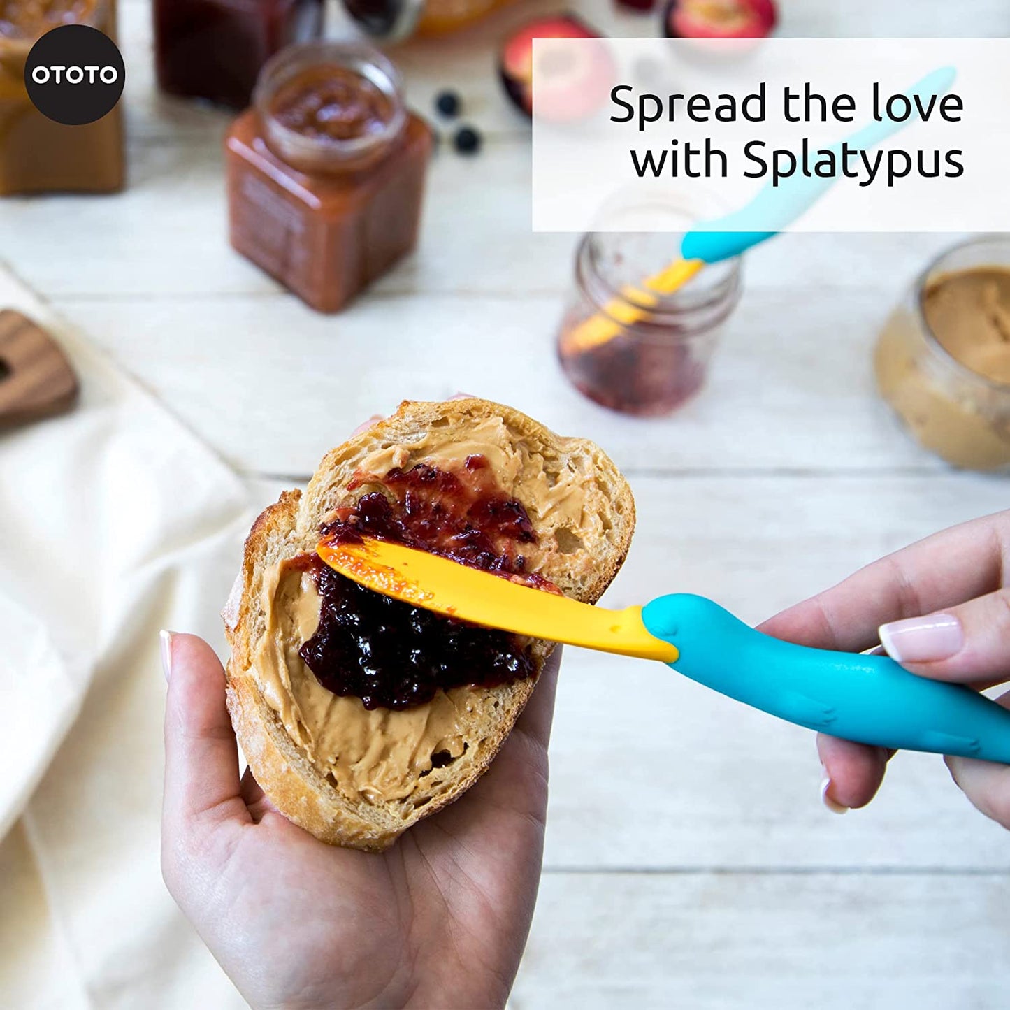 A pair of hands is spreading jam on toast using a kitchen scraper spatula.