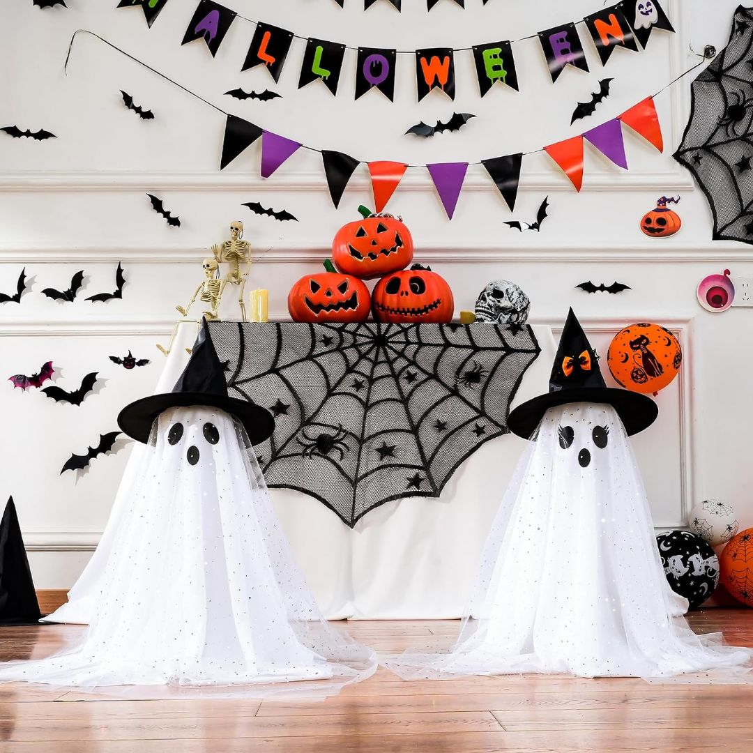Two standing ghost decorations with witch hats displayed among pumpkins, bats and Halloween party decorations