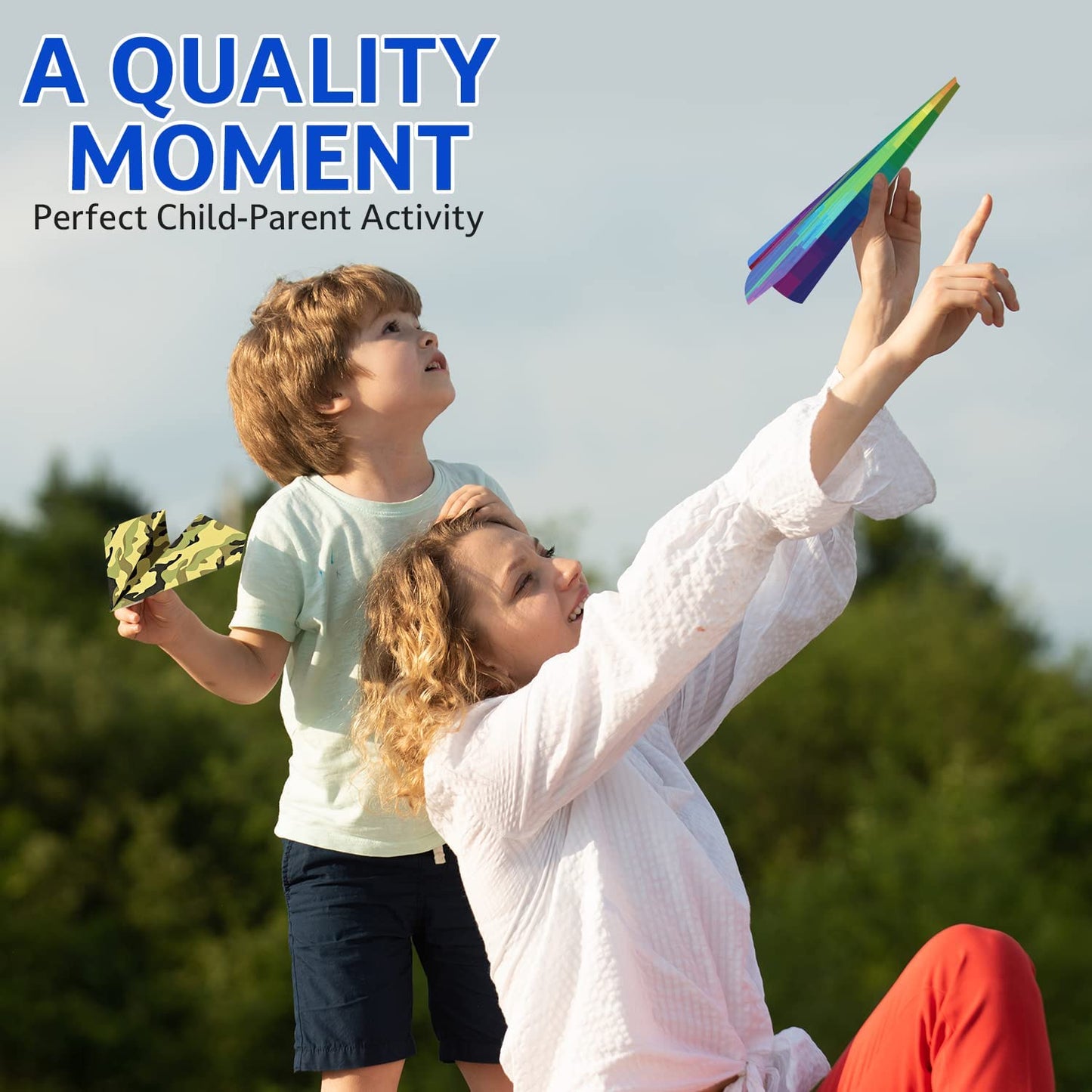 A mother and child are outdoors playing with paper airlplanes.