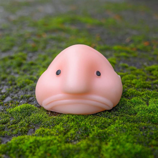 Pink squishy toy blobfish on a green mossy background