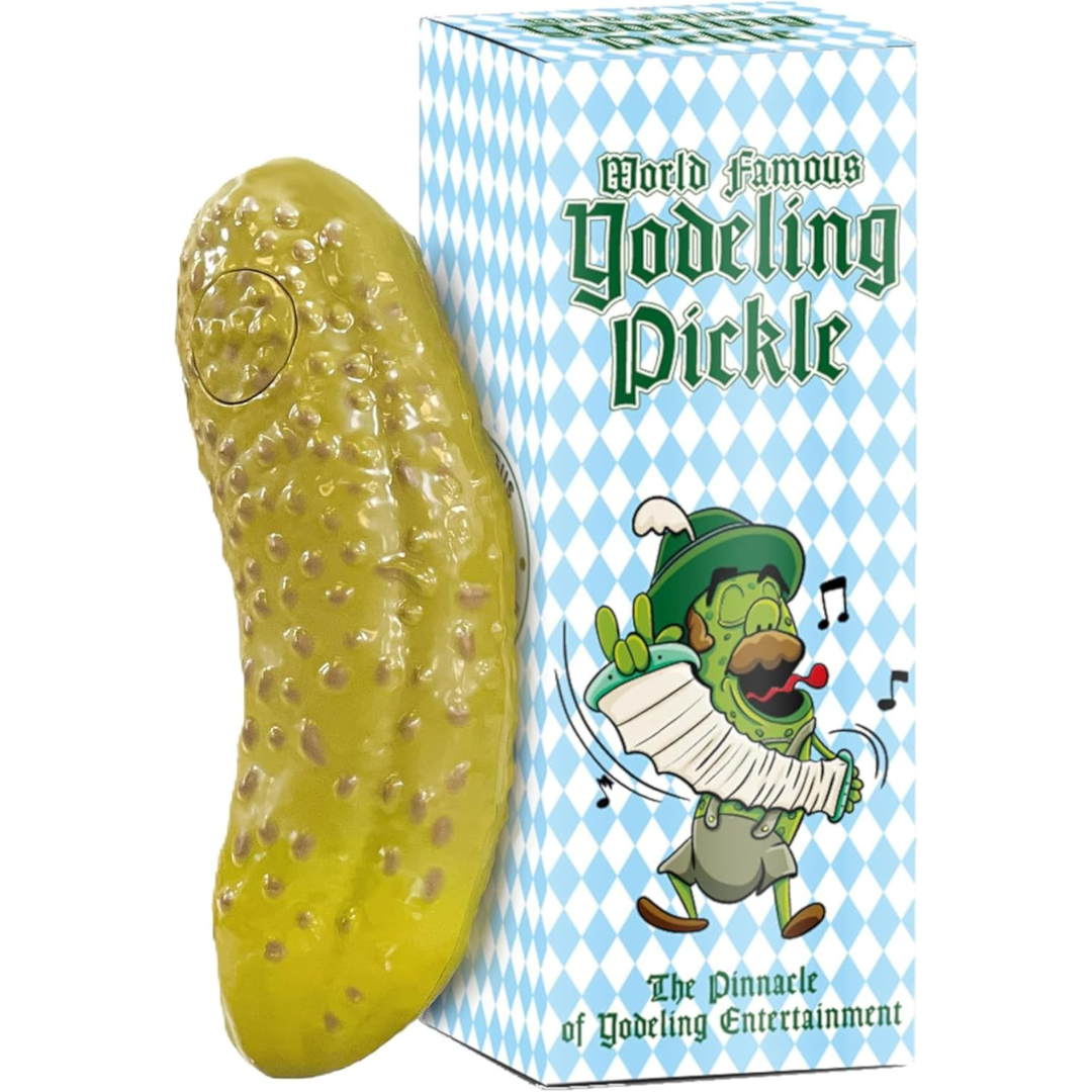 Toy yodeling pickle next to its box, which features a cartoon pickle in German attire playing an accordion and yodeling.