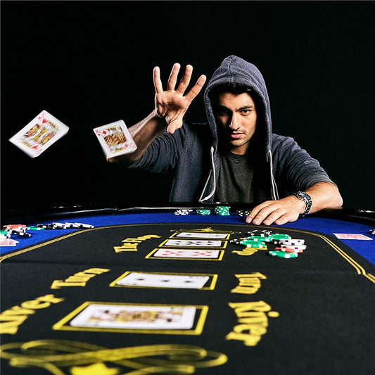 A man is flicking playing cards towards the camera while sitting at a 10 player poker table.