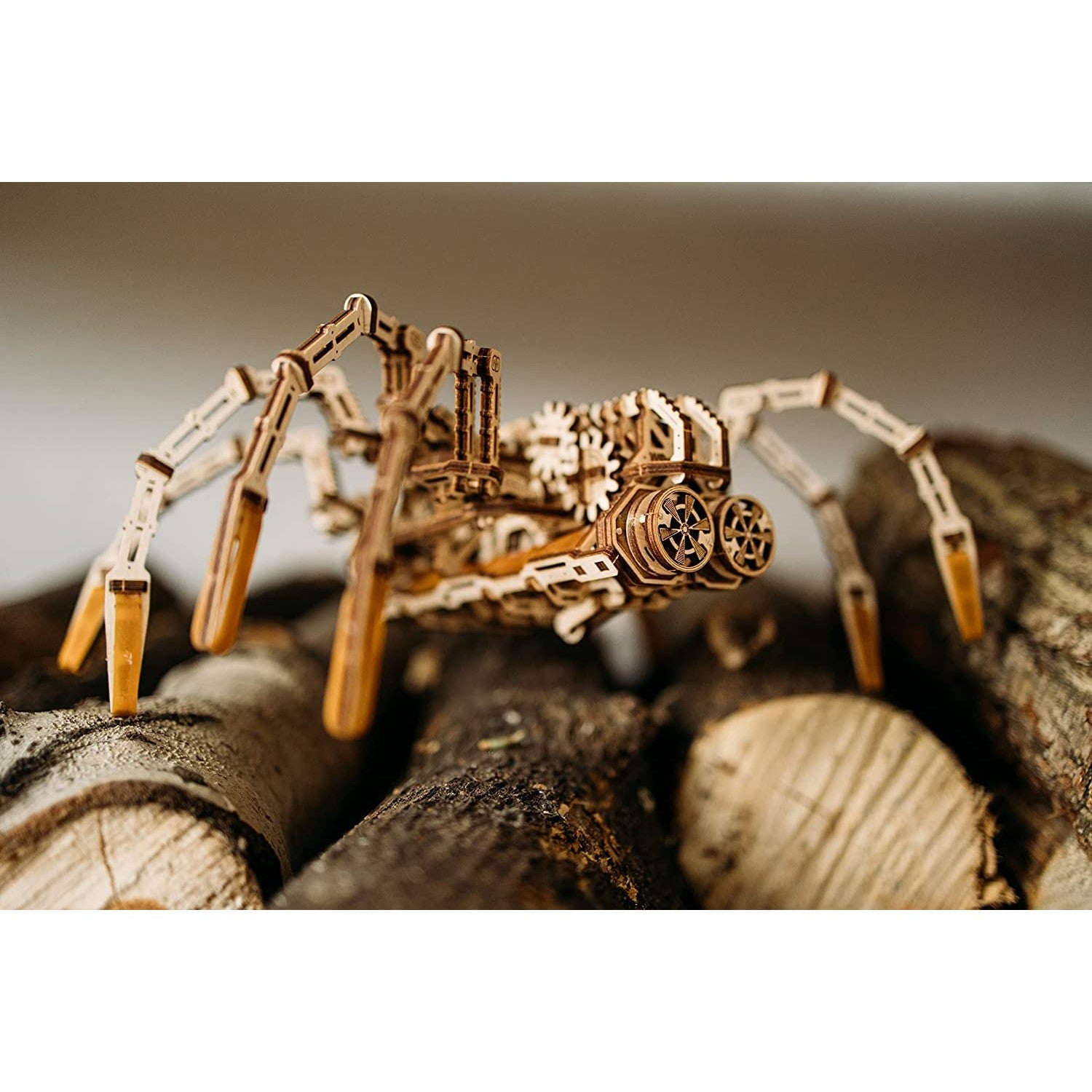 A 3D spider puzzle made out of wood is sitting on a pile of wooden logs.