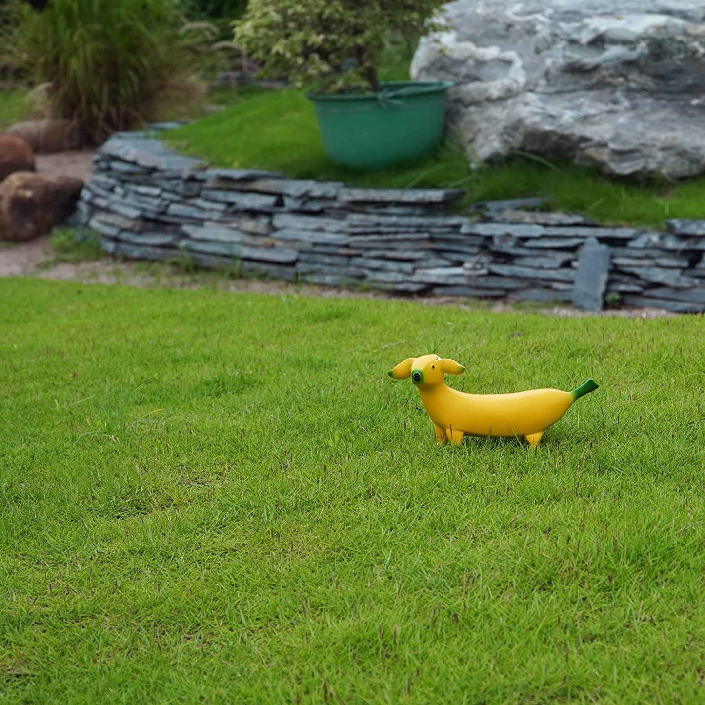 A garden ornament which is called a banana dog. The ornament is shaped like a yellow banana but has a dogs head.