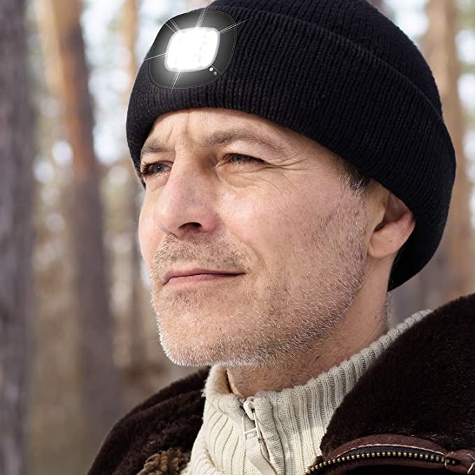 A man is outdoors wearing a black beanie which has an inbuilt torch in the front.
