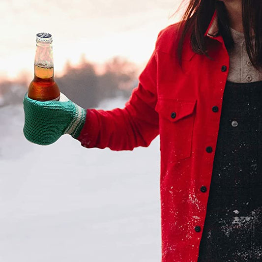 A woman in a red coat is wearing a beer mitt while holding a beer to keep her hands warm. The woman is outdoors in the snow.