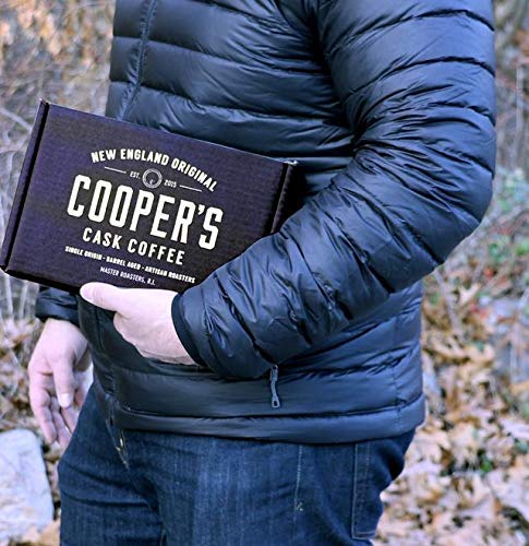 A man is holding a box set of Coopers Cask Coffee in his arm.