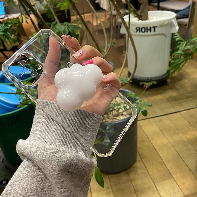 A phone case grip holder. The case is clear with a white cloud on the back as a grip. The phone is in a persons hand.