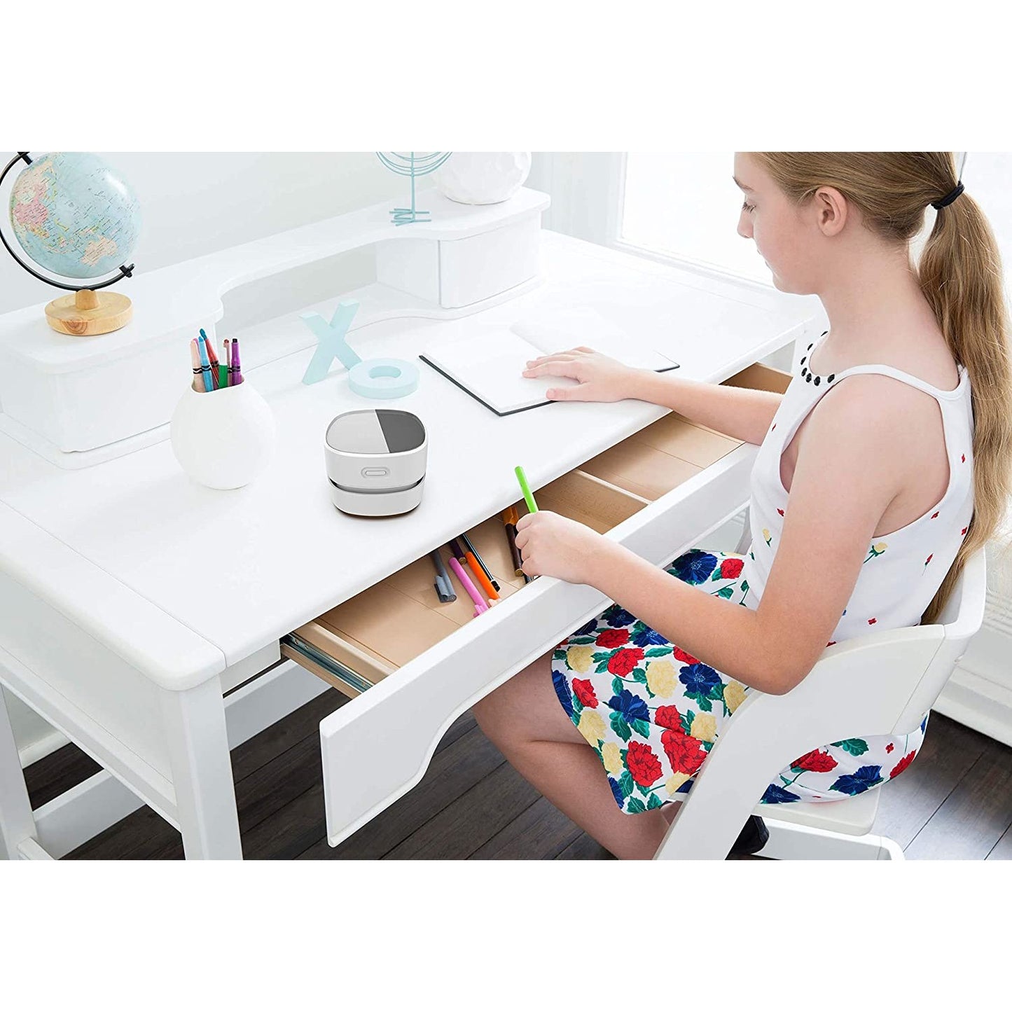 A desktop vacuum cleaner on a study desk with a woman sitting in a chair.