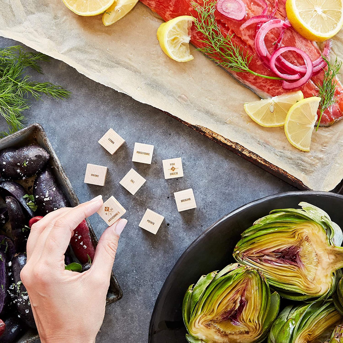 A set of foodie dice in the centre of a table surrounded with plates of food. Foodie dice are like regular dice which help you to decide what to cook for dinner.