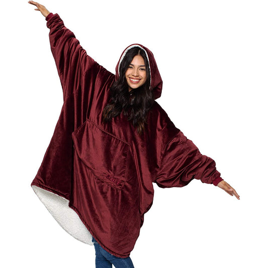 A smiling woman wearing a burgundy colored giant oversized blanket
