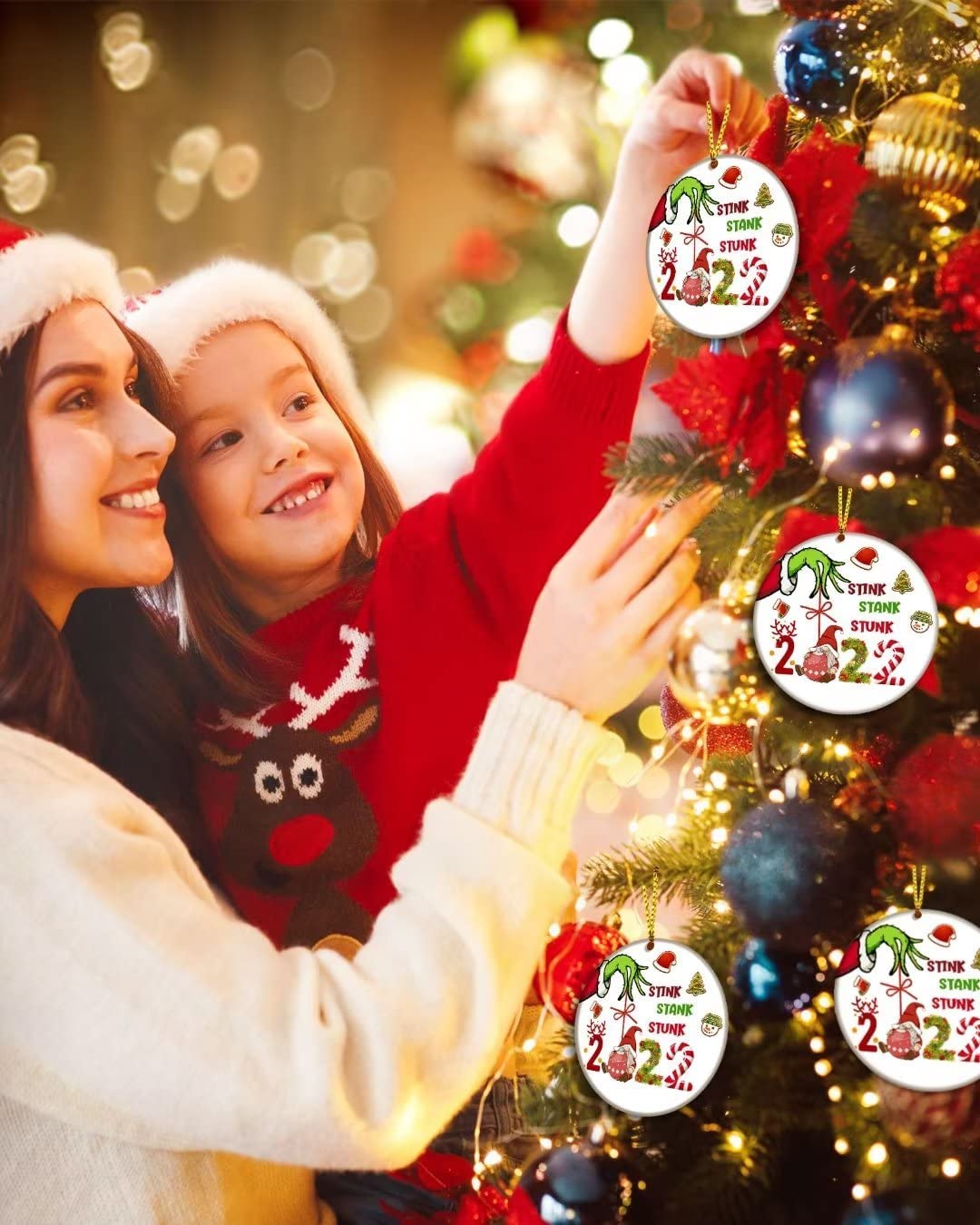 A mother and child are hanging up Christmas tree ornaments which feature the Grinch and says, 'Stink, stank, stunk, 2022'