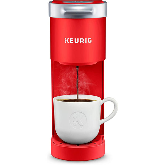 A red colored Keurig K-Mini which is brewing coffee into a white cup.