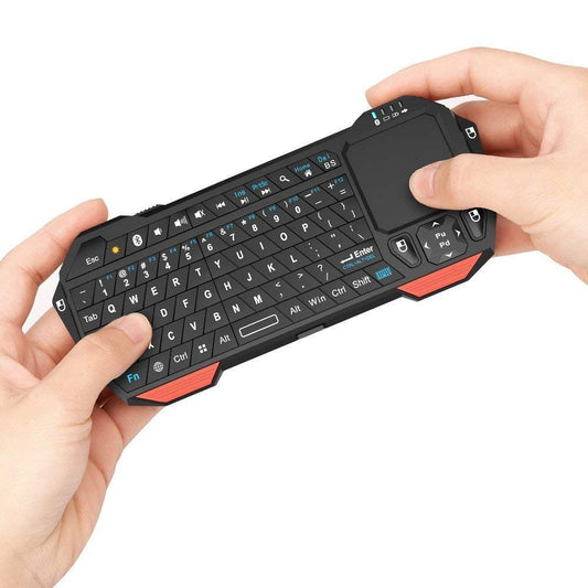 A pair of hands are holding a mini Bluetooth keyboard with touchpad