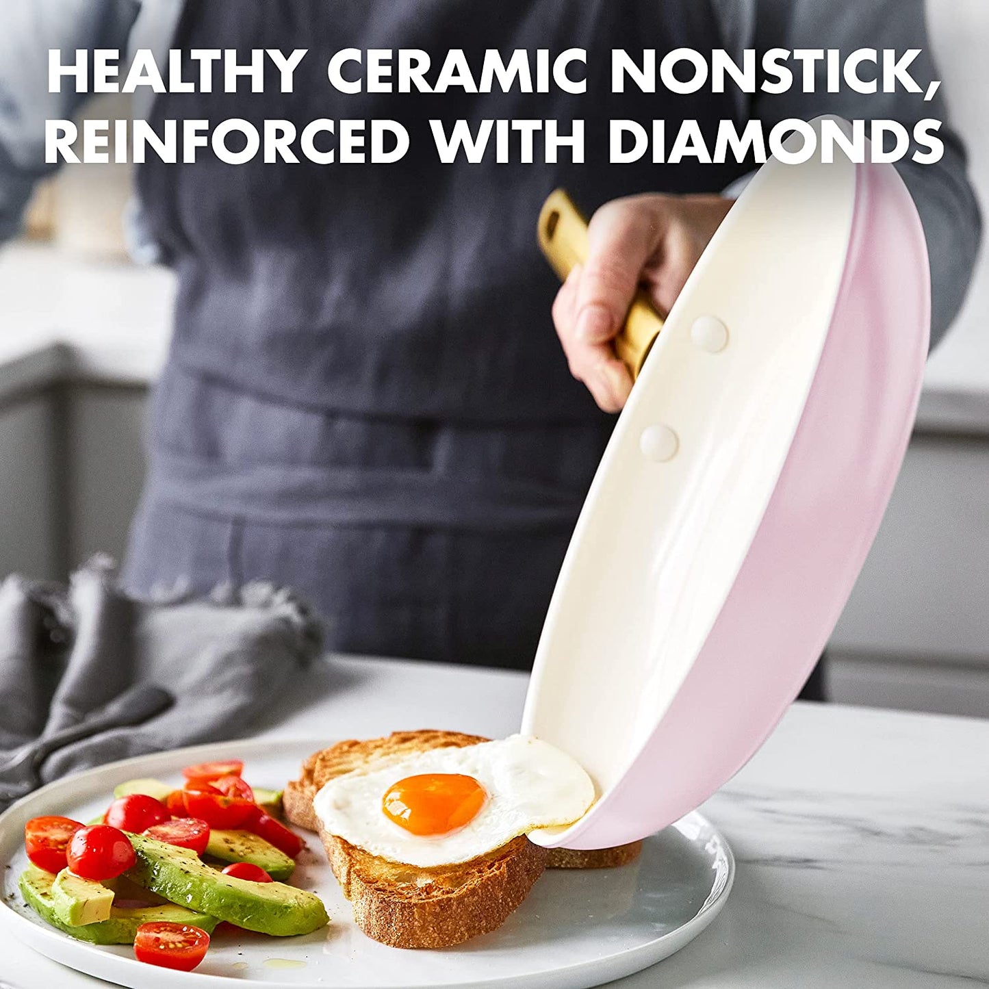 A chef is sliding a fried egg out of a pink pan onto a slice of bread with some avocado and tomato on the side.