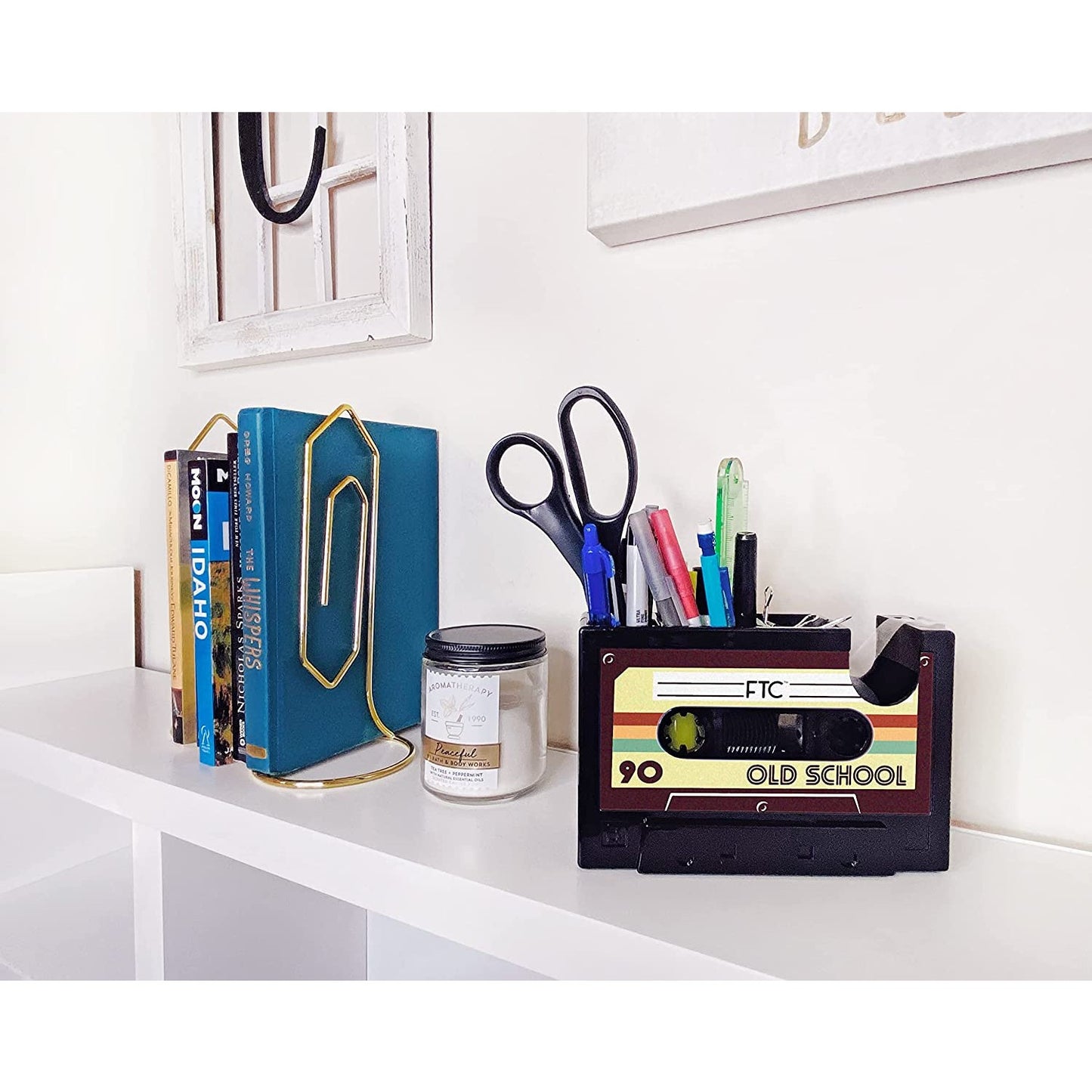 A retro cassette tape dispenser and stationary holder on a shelf.