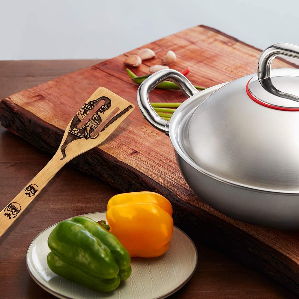 A bamboo kitchen spatula featuring a burnt in image of Darth Vader and two stormtroopers. The spatula is resting on a wooden chopping board.