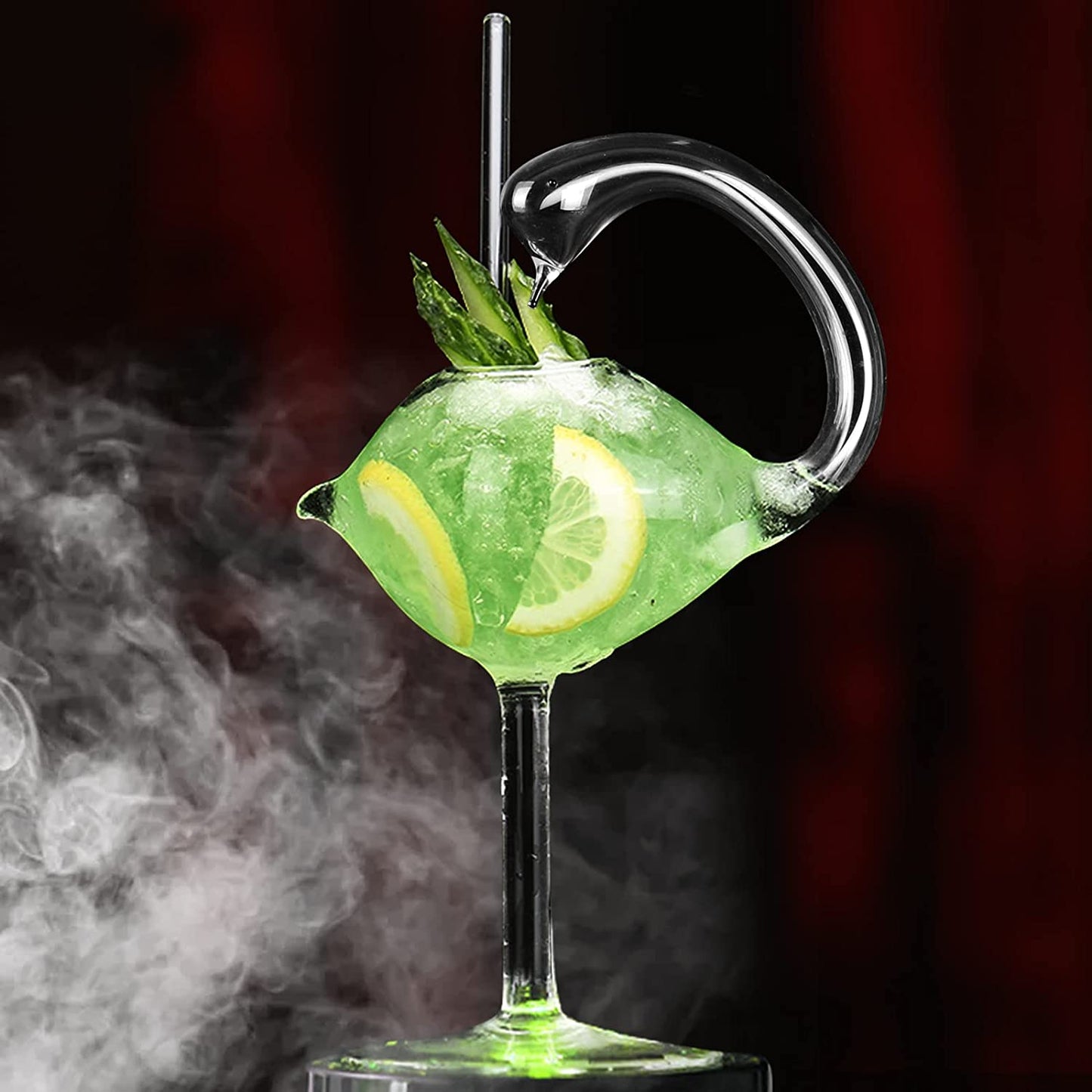 A swan shaped cocktail glass filled with a green drink with lemon slices and cucumber.