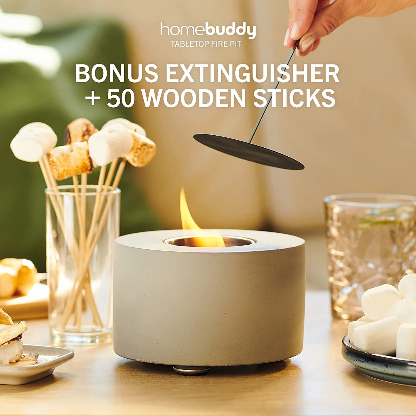 A Homebuddy mini tabletop fire pit with roasted marshmallows nearly and a persons hand about to extinguish the flame.