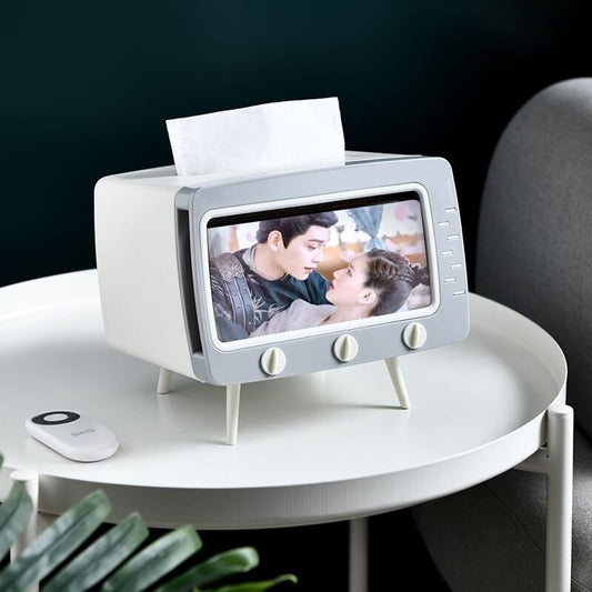 A white and grey tissue box shaped like a TV set resting on a table
