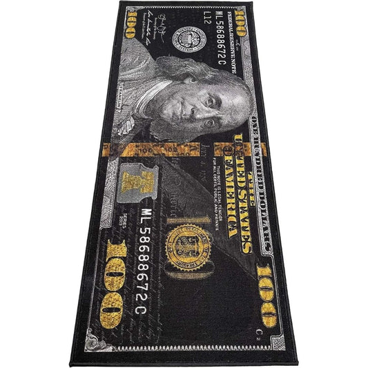 A rectangular black rug printed with a detailed 100 US dollar bill design, featuring gray portrait engraving, gold '100' numerals, and black ornamental border details, shown on a plain white background.