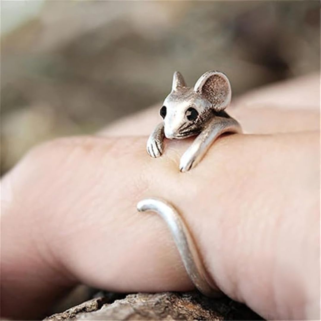 Silver mouse-shaped ring on a person's finger with a natural background