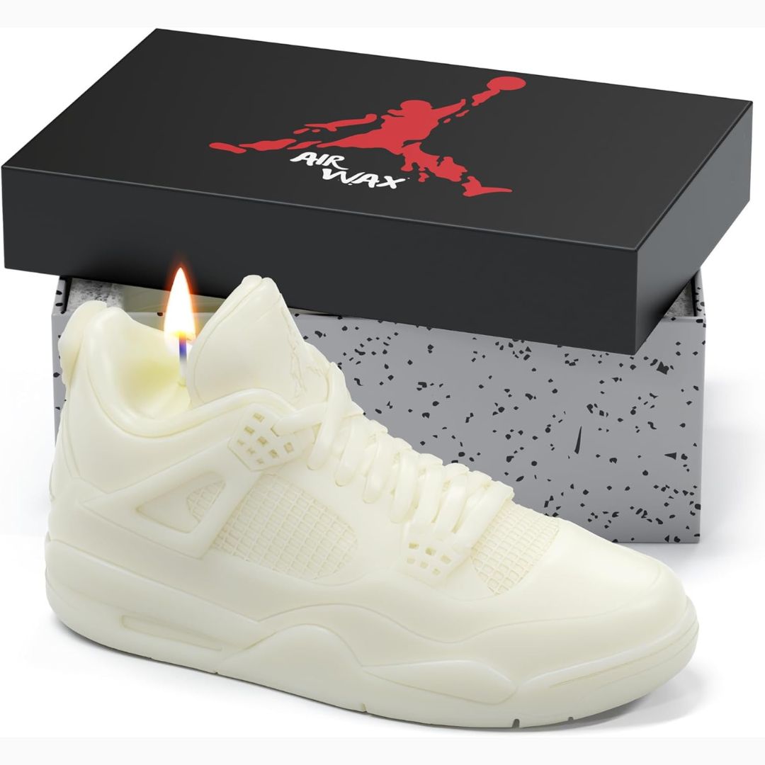 White shoe-shaped candle with a lit wick in front of an Air Jordan box.
