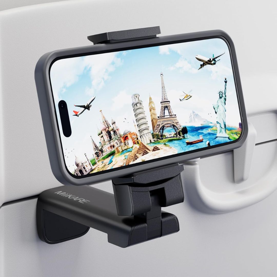 A black airplane phone mount clip holder holding a smartphone, shown mounted on a white airplane tray table.