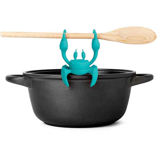 Aqua the crab silicone utensil holder holding a wooden spoon on a black pot.