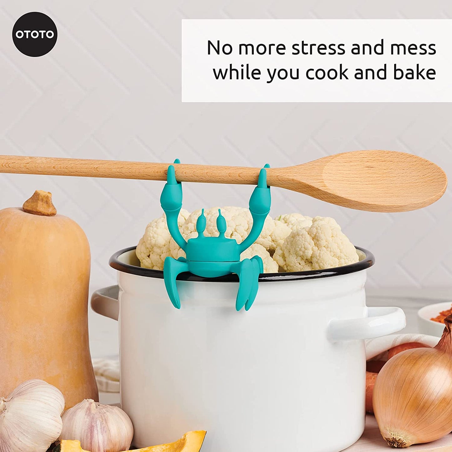 Aqua the crab silicone utensil holder sitting on the edge of a white pot.