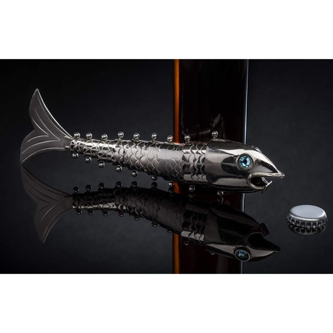 Articulating silver fish beer bottle opener displayed on a reflective black surface beside a bottle cap