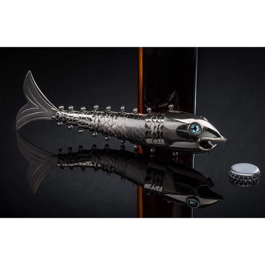 Articulating silver fish beer bottle opener displayed on a reflective black surface beside a bottle cap