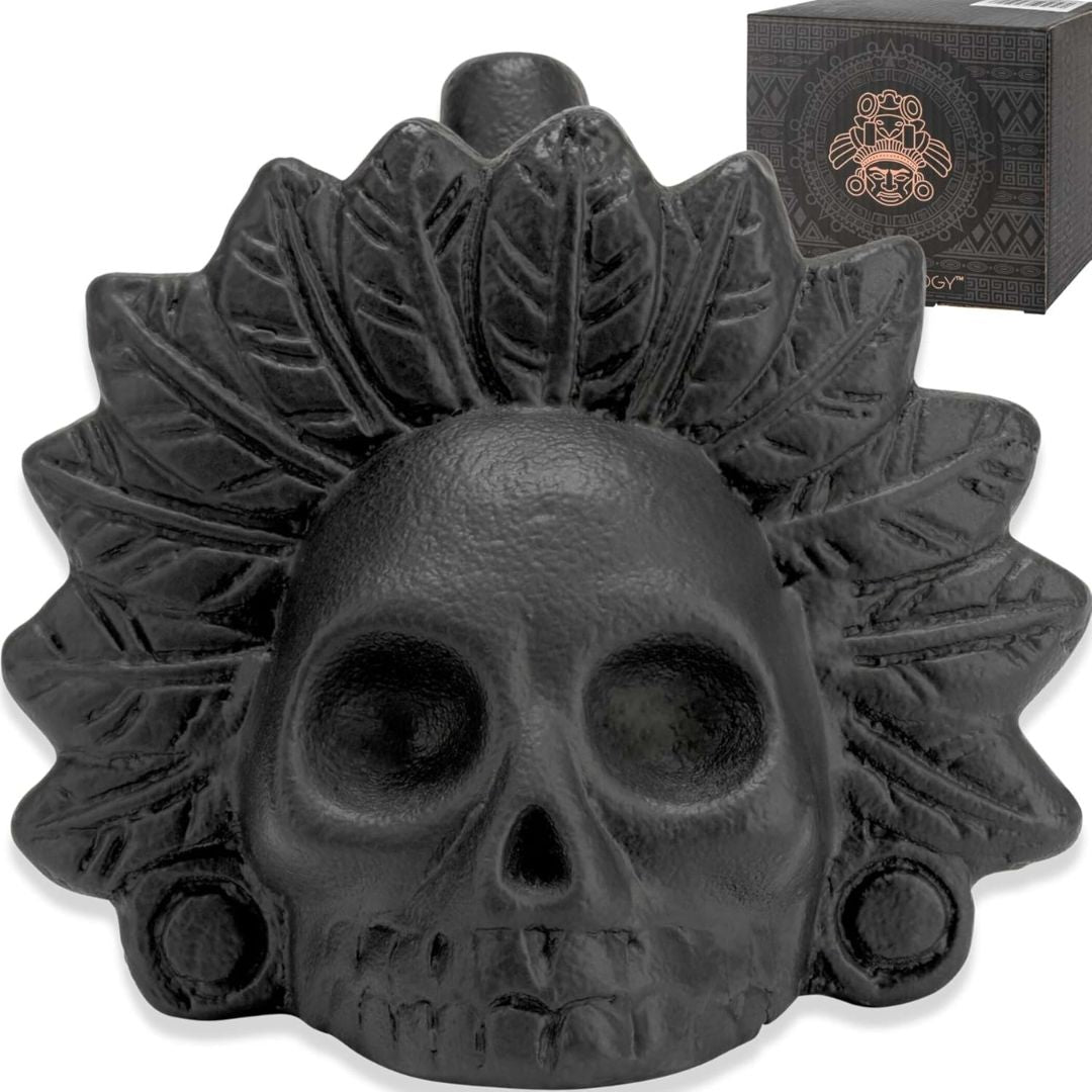 Black skull-shaped axtec ceramic death whistle with leaf-like decorations on a white background
