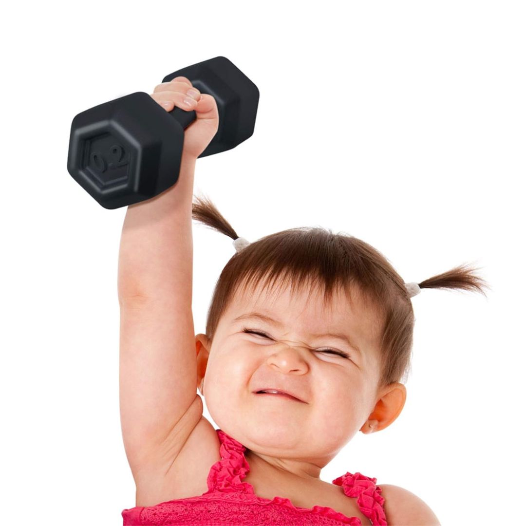Child lifting a small black dumbbell shaped baby rattle against a white background