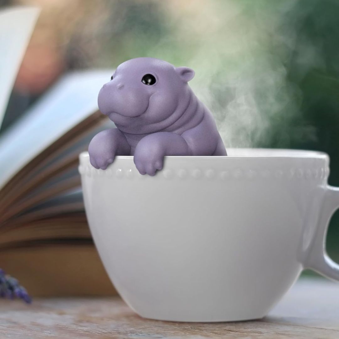 Purple baby hippo tea infuser in a white mug with a blurred background
